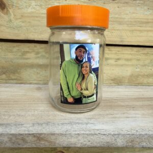 A jar with a photo of a couple on a wooden surface.