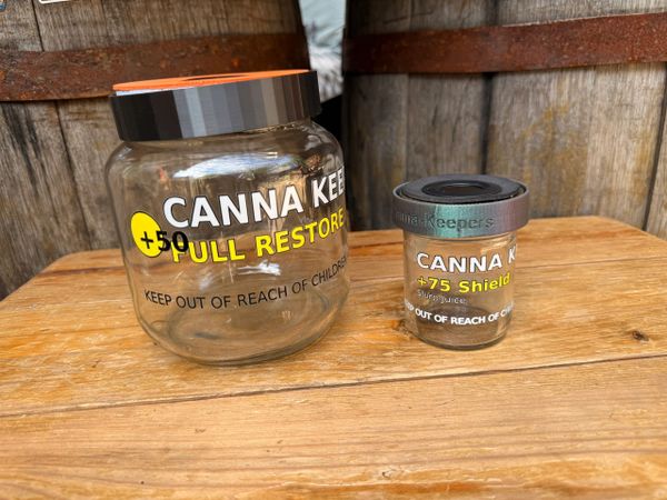 Two Canna Keg Soul Restore containers on a wooden surface.