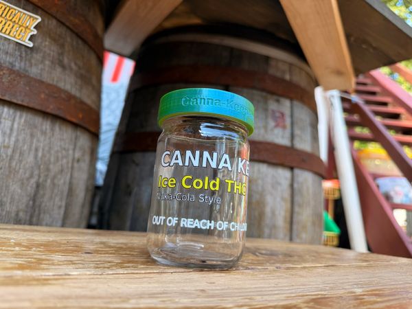 A glass jar labeled 'Cannabis Ice Cold THC' on a wooden surface.