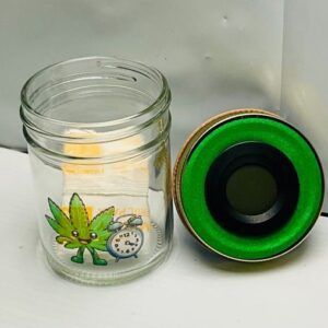 A glass jar with a green lid and cartoon designs of a leaf, dog, and clock.