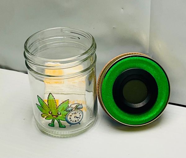 A glass jar with a green lid and cartoon designs of a leaf, dog, and clock.