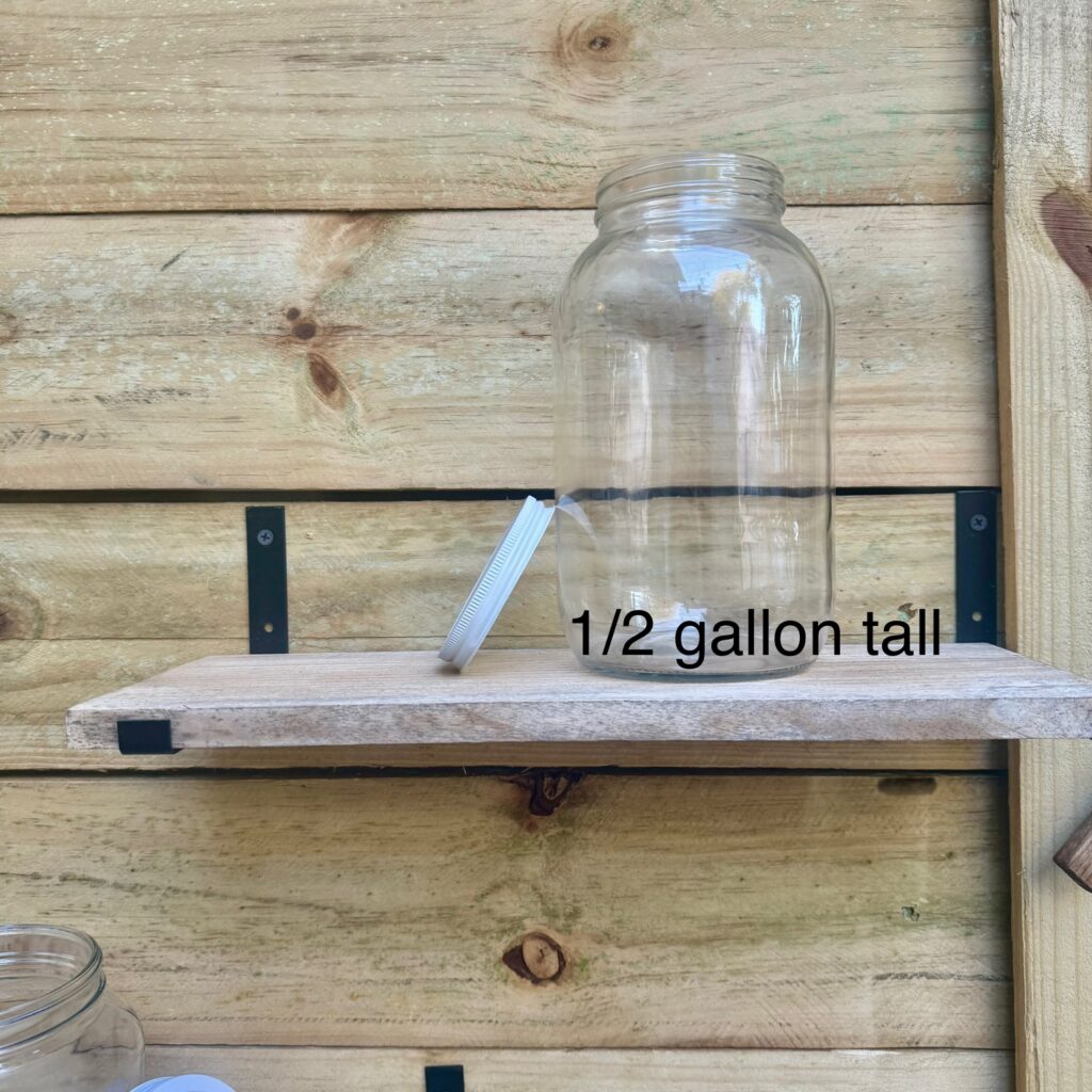 A 1/2 gallon glass jar on a wooden shelf mounted outdoors.