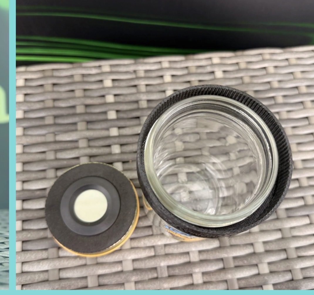 Open glass jar and lid on woven mat